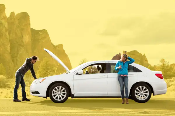 Couple standing with their broken down car.