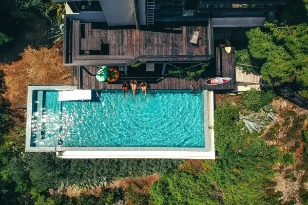 Aerial view of a three friends relaxing by the pool at a home