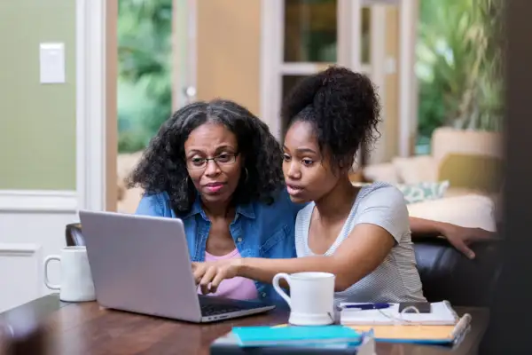 Young woman shows her mom something on laptop.