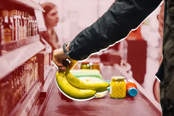 A person putting some bananas and other groceries on the conveyor at a store checkout