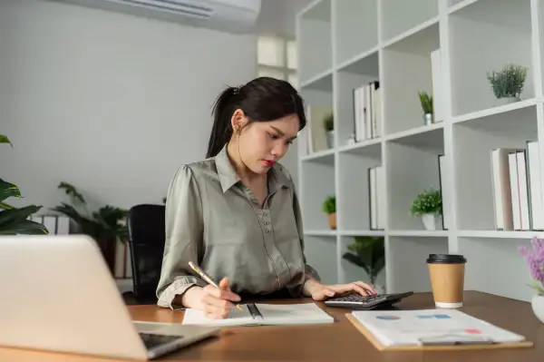 Woman using a calculator and writing on a notepad