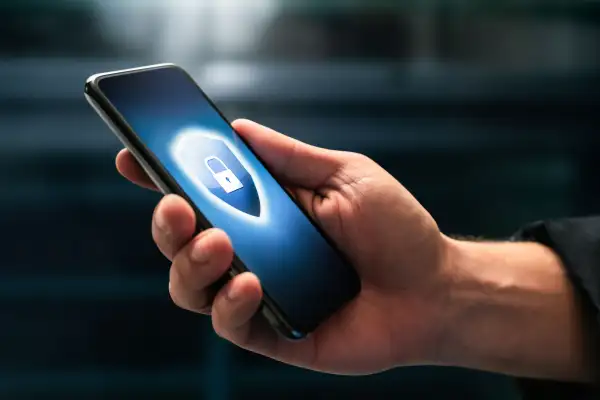 Close-up of a hand holding a smartphone with a logo of a shield and a lock