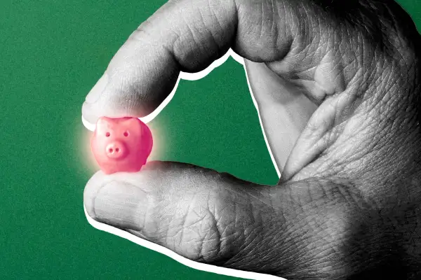 A hand holding a miniature piggy bank.