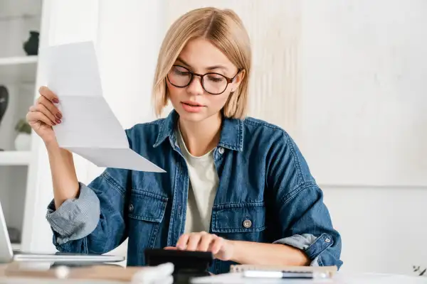 Woman looking at a bill while using a calculator