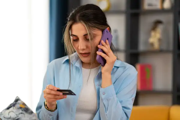 Woman holding a credit card while talking on her cell phone