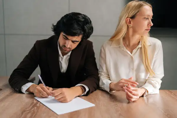 Portrait of sad couple signing divorce papers in an office.