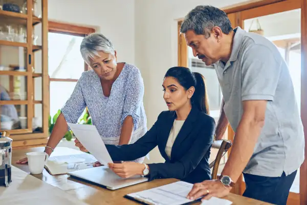 Woman showing portfolio options to a senior couple at their home