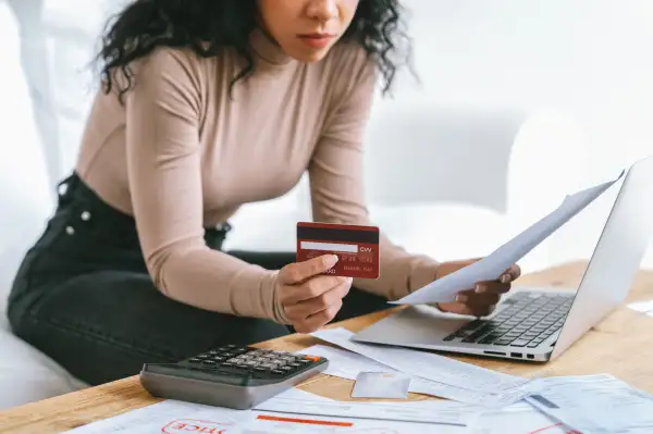 Close-up of a woman holding a credit card in one hand and bills in the other