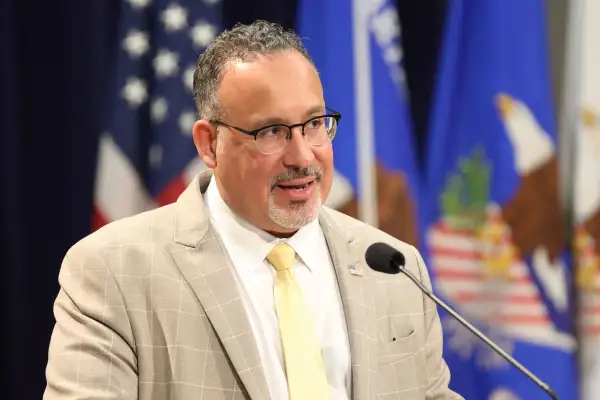 Secretary of Education Miguel Cardona speaking on a podium