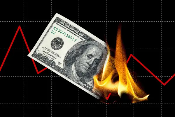 Photo collage of a hundred dollar bill on fire with a red stock line in the background