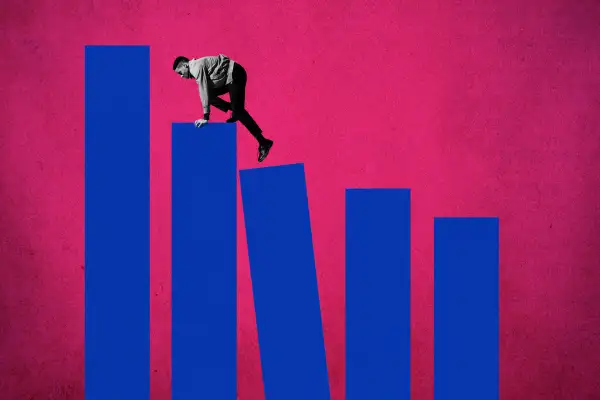 Side view of young man climbing up on blue bar graphs against a pink background