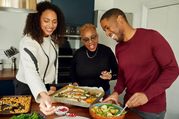 Mother and two adult children preparing home cooked meal in the kitchen