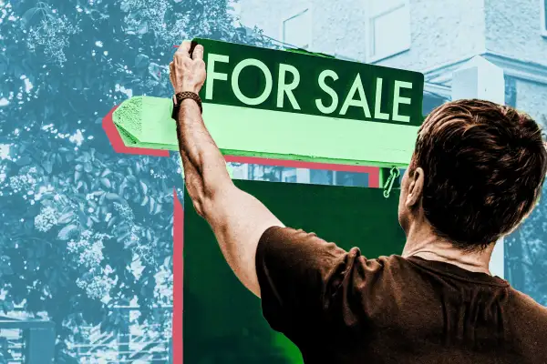 Man reaching for 'For Sale' sign in front of house