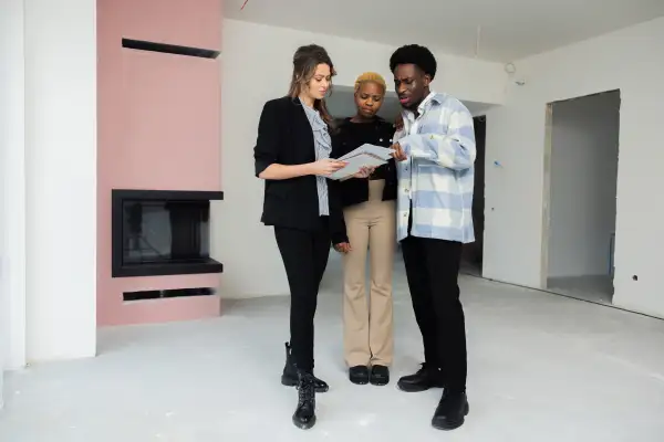 Real estate agent showcases a beautiful home to a couple while holding a detailed floor plan in her hands