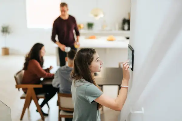 Adolescent girl using digital tablet mounted on wall by family at a smart modern home