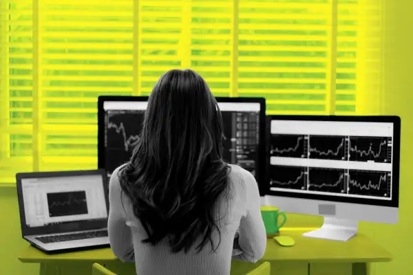 Woman form behind, looking at a computer screen with stock charts