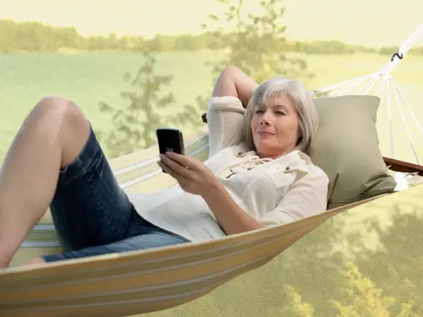 Senior woman on a hammock looking at her cell phone