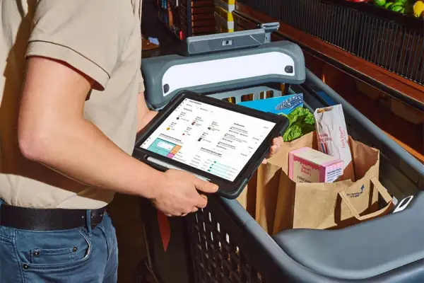 Close-up of a man using a smart Caper Cart while shopping for groceries