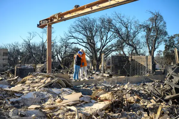 Two women hug while visiting what is left of their home, destroyed by the Palisades wildfire