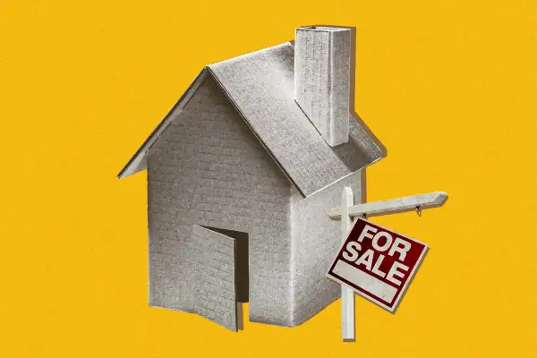 Cardboard house with for sale sign falling apart