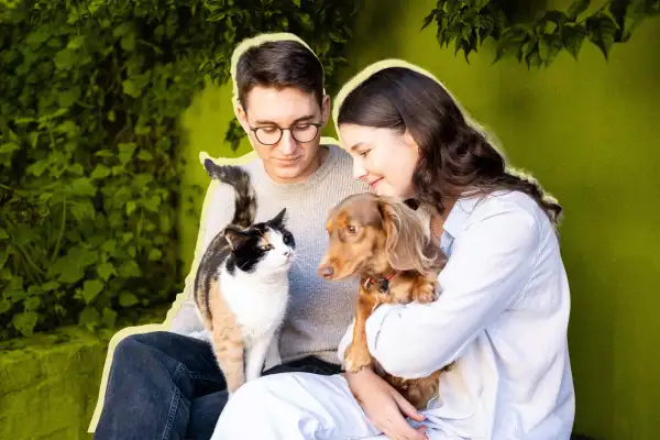 A couple sitting with a cat and dog on their laps